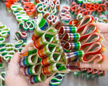 tropical fruit punch flavored rainbow colored ribbon candy filled with chocolate held in 2 hands